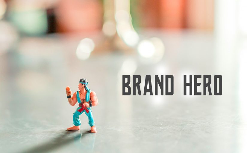 Brand hero pod postacią figurki stoi na stole, a obok jest teks "Brand Hero"